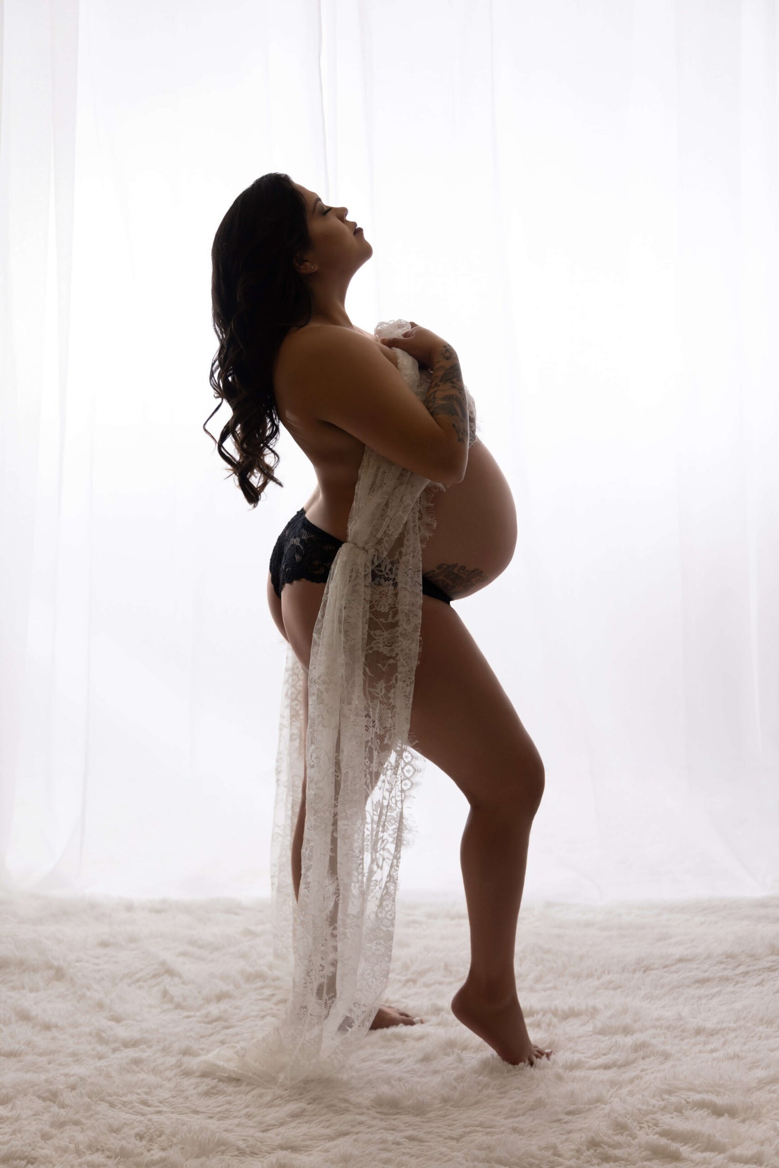 Pregnant woman in silhouette pose for boudoir photoshoot.